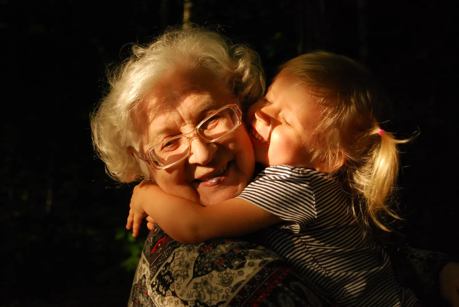 Une grand-mère et une enfant s’enlacent dans une lumière chaude.